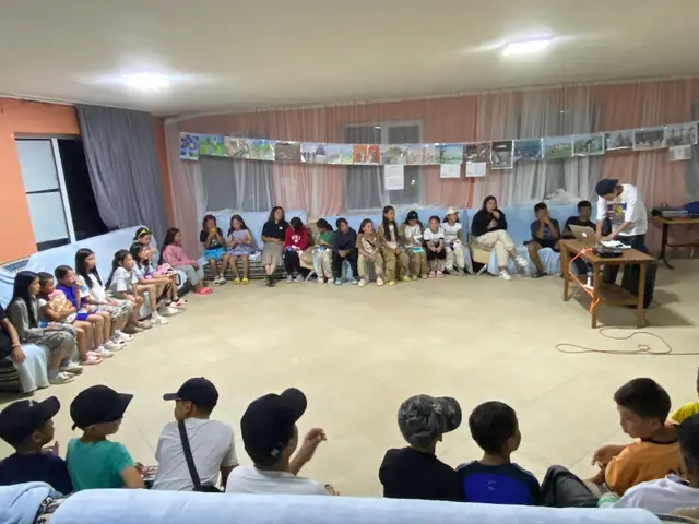 Children seated in a circle during a camp gathering