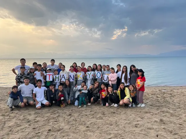 Camp children holding a thank you sign on the beach