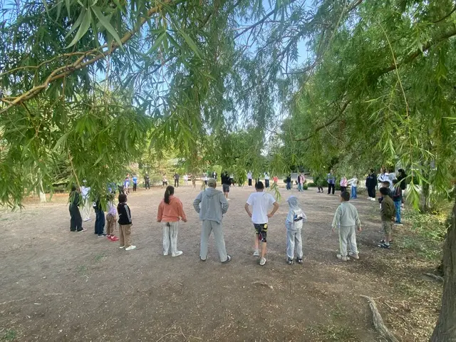 Children gathered under willow trees at dusk